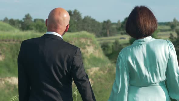 Panning Shot of Happy Relaxed Couple Admiring Nature Standing in Sunshine Holding Hands