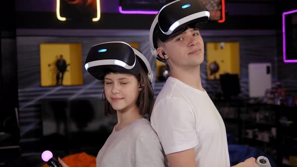 Teenagers Using a VR Headset with Goggles and Hands Motion Controllers