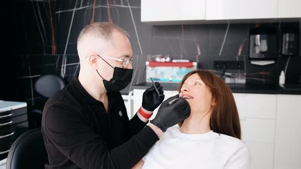 A Professional Dentist in a Protective Mask Works with a Patient in the Clinic