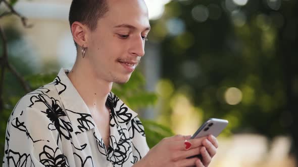 A hipster man with earrings taking selfie-photo using hphone standing