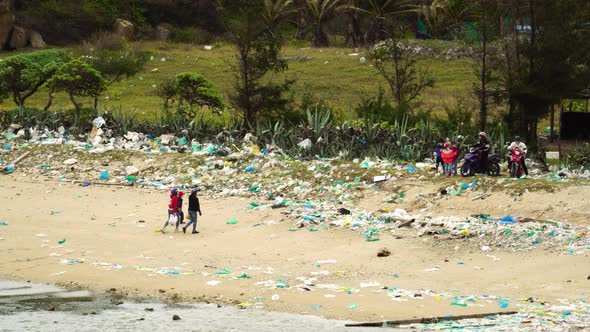 Southeast Asia villagers walking on dirty polluted beach full of plastic trash