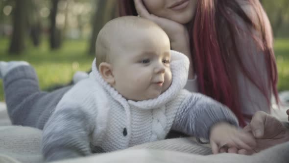 Closeup of Charming Cute Caucasian Boy Lying on Blanket Playing with Smiling Young Father and Mother