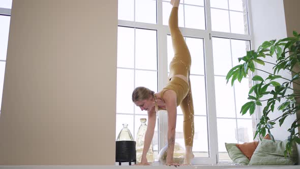 Young Woman in Sports Outfit Does Vertical Split on Sill