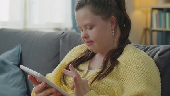 Girl with Down Syndrome Browsing the Web on Tablet at Home