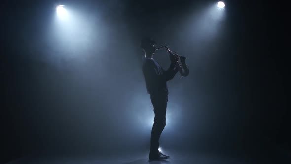 On a Dark Smoke Background Young Musician Playing the Saxophone