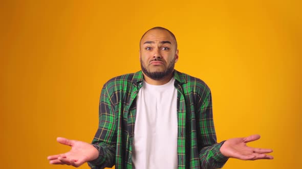 Clueless African American Man Gesturing He Doesn't Know Against Yellow Background