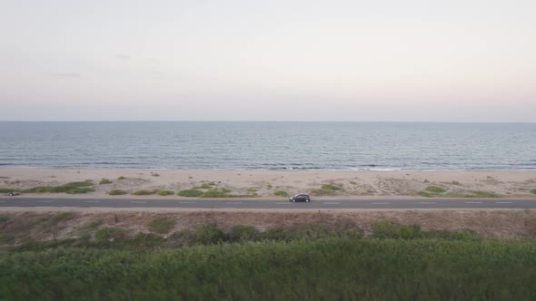Side View of Travelers Car Driving on the Seashore in the Morning