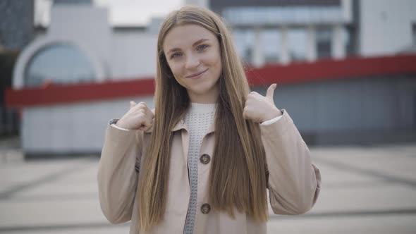 Happy Young Woman Showing Thumbs Up and Smiling at Camera. Portrait of Satisfied Cheerful Caucasian