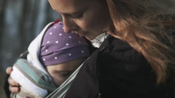 Beautiful close-up of mother holding sleeping child closely on cold day