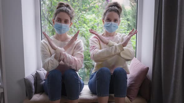 Exhausted Twin Sisters in Coronavirus Face Masks Crossing Hands Gesturing No Shaking Heads