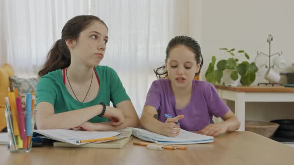 Teenage girl helping her young sister with homework during the COVID-19 pandemic