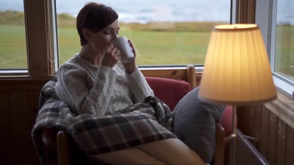A Woman Is Drinking Tea in an Armchair at Home.
