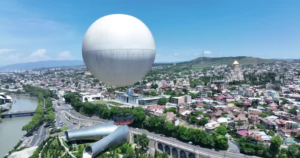 Flying over white balloon in the center of city. Morning cityscape of Tbilisi
