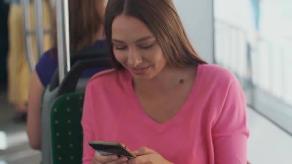 Young and Happy Woman Using Smartphone While Sitting Near the Window in the Public Transport During