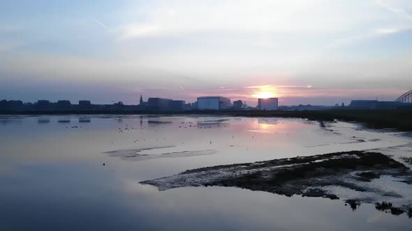 Birds resting at a small lake with a sunrise behind skyline in the background