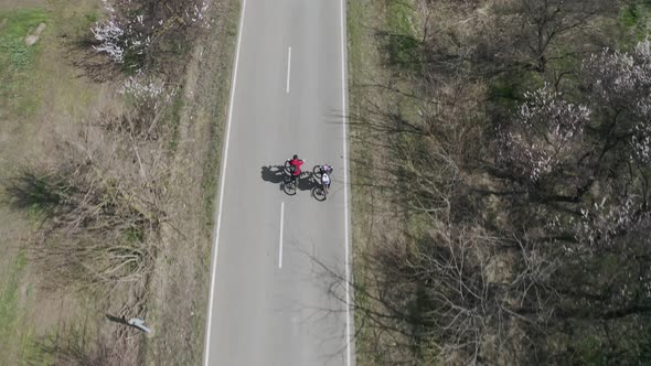 Aerial View of a Happy Couple of Cyclists Riding Along the Road