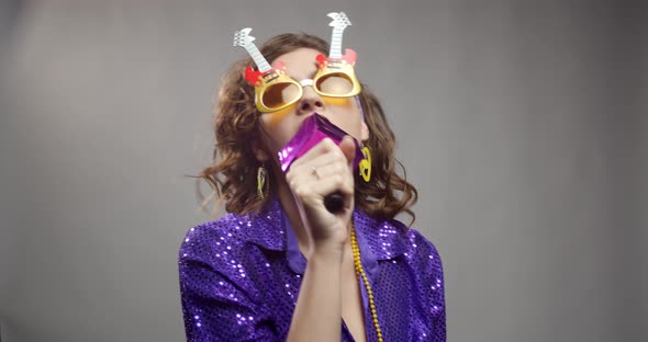 Happy woman with a mic in hand is singing at the retro dance party, 4k