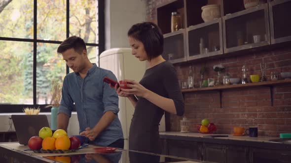 Two People Holding Cups and Use Gadgets Indoors