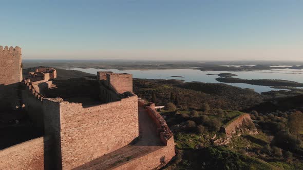 Flying past the walls with high contrast shadows on the Castle of Monsaraz during golden hour.