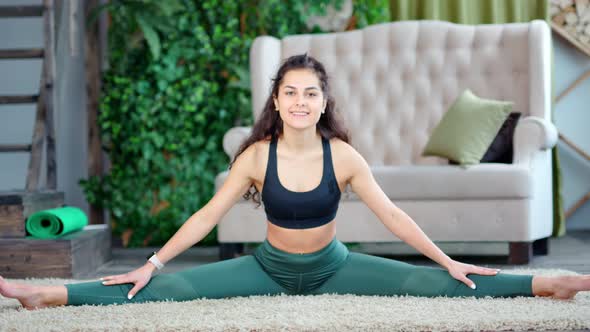 Female Pilates Instructor Smiling and Sitting in Twine Showing Amazing Stretching Full Shot