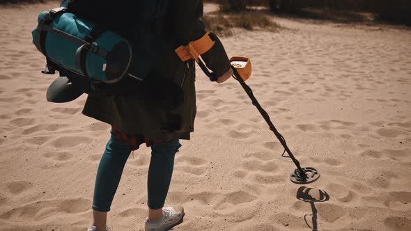 Unrecognizable Person Scanning the Sand with Metal Detector To Find Lost Precious Metals.