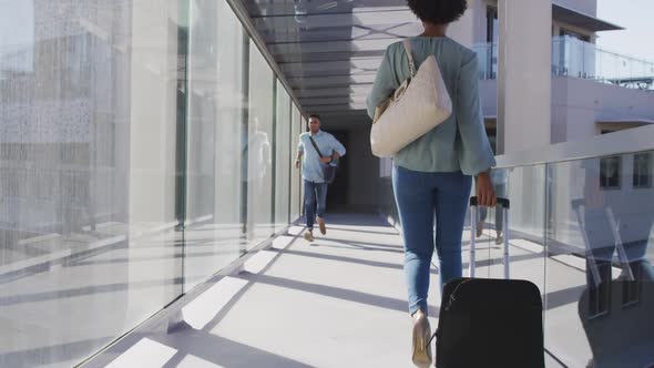 Video of diverse businessman and businesswoman walking with suitcase