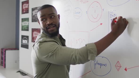 Video of happy african american male teacher at blackboard during math lesson