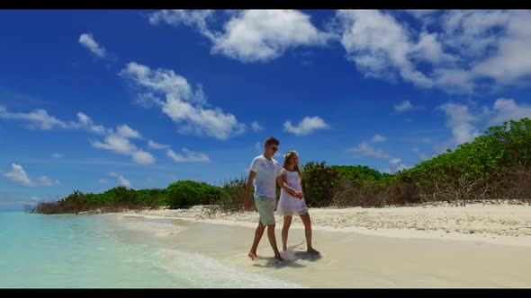 Guy and girl suntan on paradise seashore beach lifestyle by blue green sea with white sand backgroun