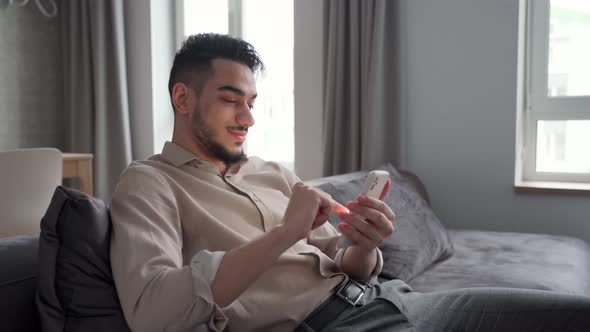 Young Man Using Phone and Internet Technology Sitting on Sofa Rest at Home