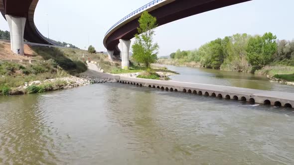 Aerial Low Flying Along Llobregat River Underneath Flyover Road In Catalonia