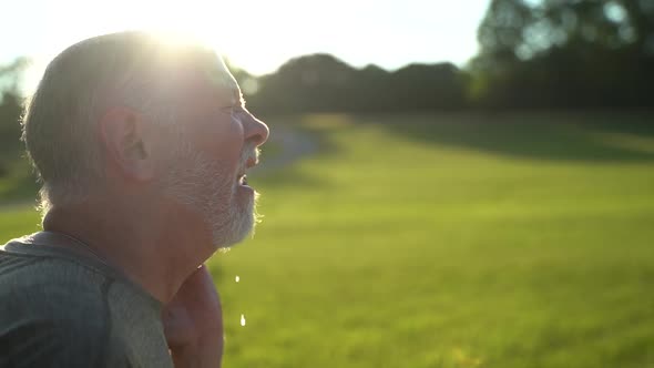 Slow motion sunny scene of man sneezing showing aerosol using water hose.