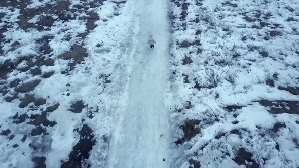 Aerial Footage of  Small Child Running Along a Snow Path in a field in Winter
