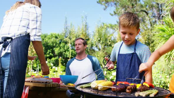 Kids grilling meat and vegetables on barbecue