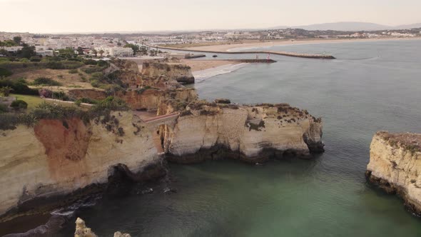 Stone arch bridge at Praia dos Estudantes against Lagos cityscape, Algarve.