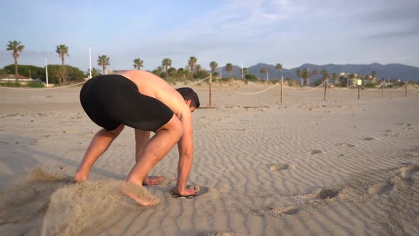 endurance training doing the frog jump on the beach seen from behind