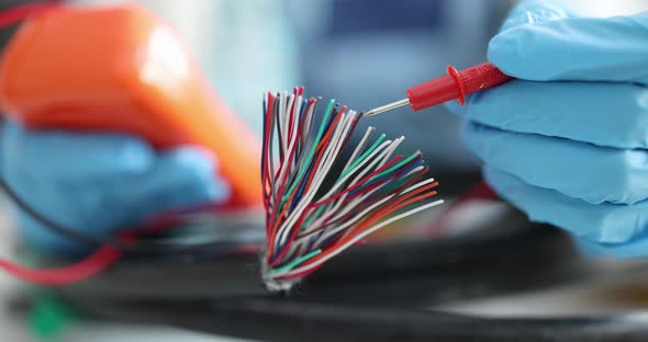 Electrician in Gloves As Tester Tests Multicolored Electric Wires