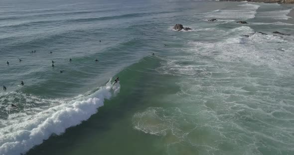 regular surfer riding a backside good wave in Guincho, Cascais with a beautiful green ocean. Aerial