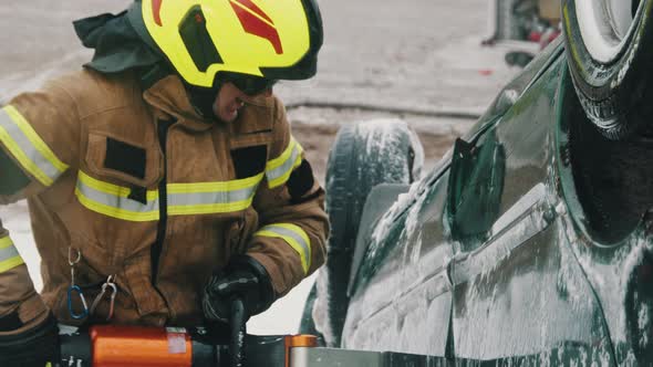 Fireman Trying To Cut Open Car Door To Save Person Involved in the Accident. Slow Motion