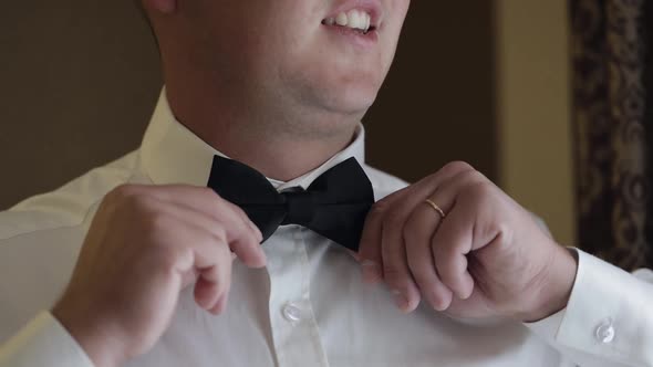 Groom Man Adjusts Bow Tie Preparing to Go to the Bride Businessman in White Shirt Wedding Day