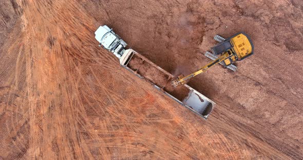 Aerial View at Excavator and Trucks Working on the Excavation Works of a Road Moving Earth It Onto