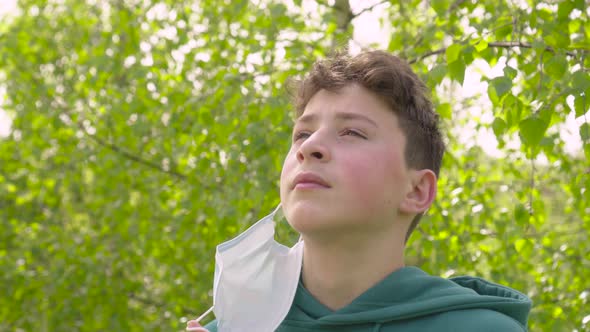 Teenager takes off his medical protective mask and takes a deep breath of fresh air