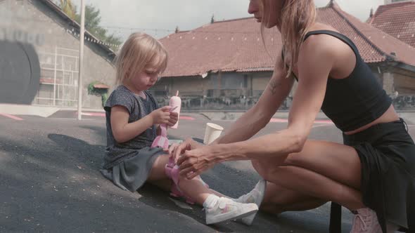 Woman Preparing Child for Roller-skating