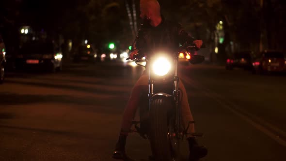 Bearded Rider Sitting on a Motocycle Turning Higly Bright the Headlight Standing on the Night City