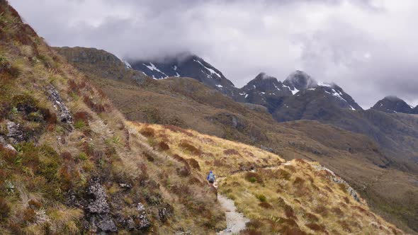 Pan, hiker crosses exposed alpine pass, Routeburn Track New Zealand