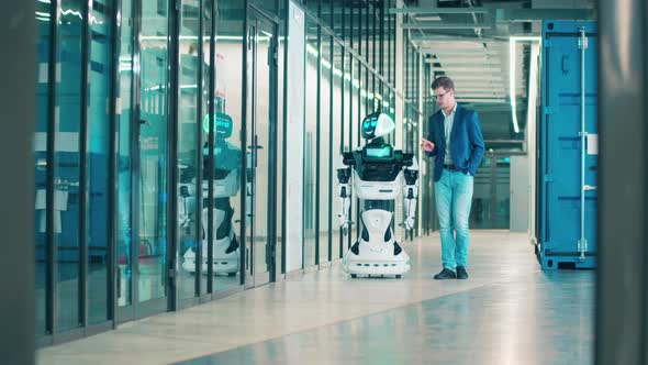 A Man and a Robot Are Going Along the Corridor