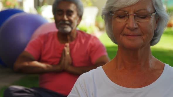 Senior friends performing yoga in garden 4k