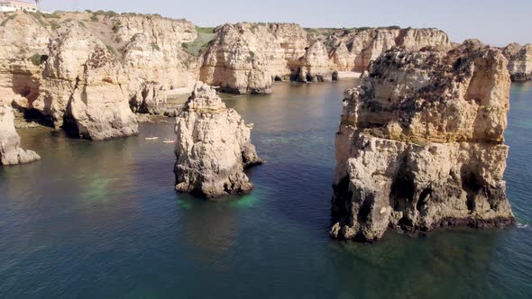 Emerald ocean calm waters with eroded rock formations and cliffs in Lagos, Algarve, Portugal