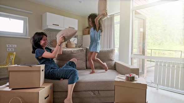 Young Mother and Her Little Daughter Jumping on Bed. Funny Pillow Fight. Play Together and Enjoy the