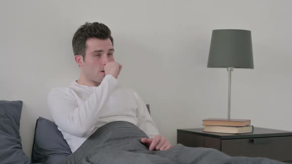 Man Coughing While Sitting in Bed