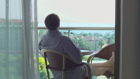 Man drinking coffee on hotel balcony.